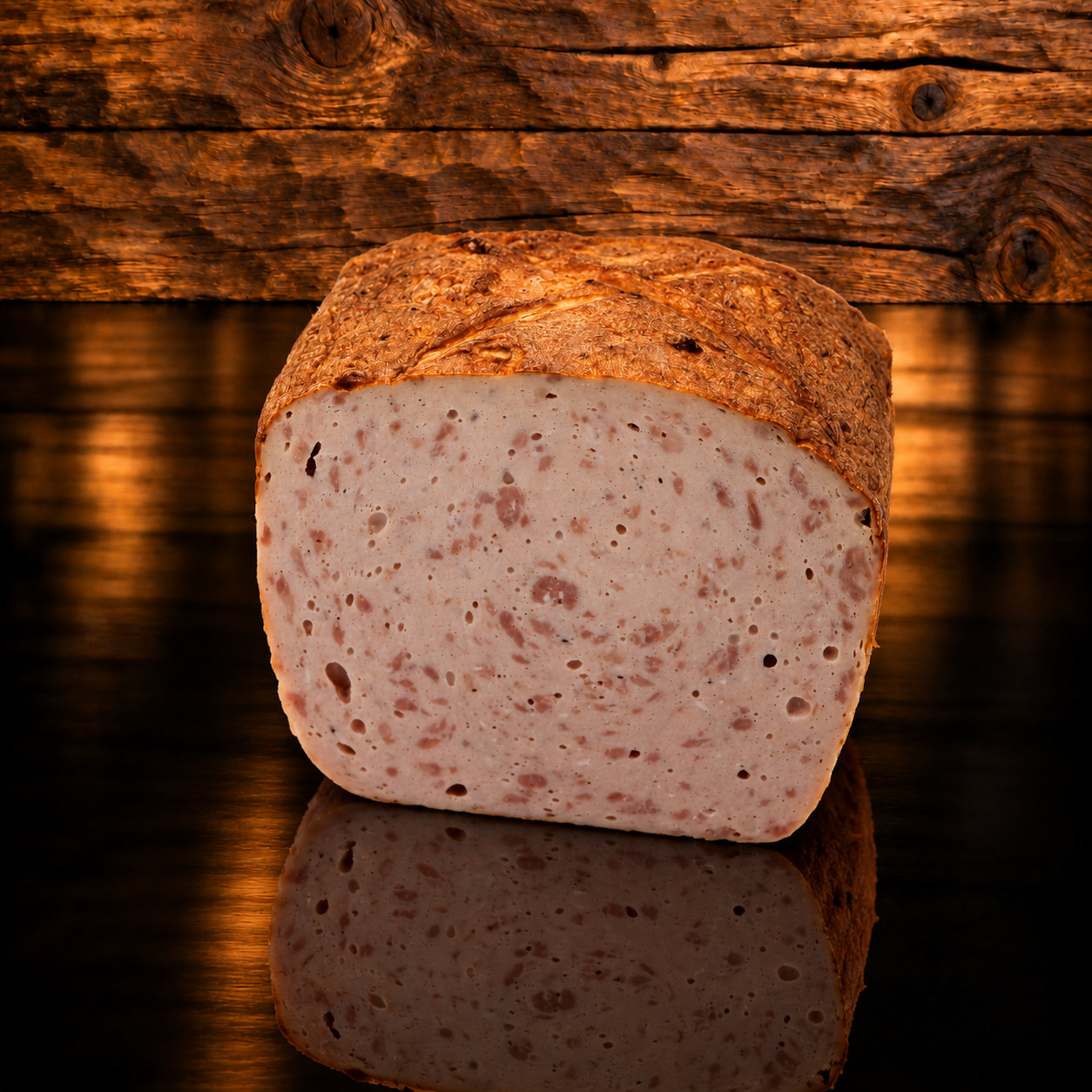 Bauernfleischkäse am Stück auf Holzschneidebrett